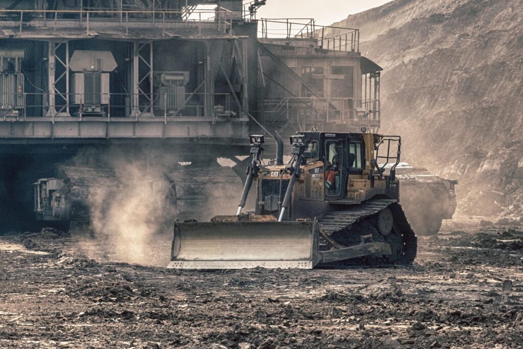 Bulldozer working on a dusty construction site near industrial buildings