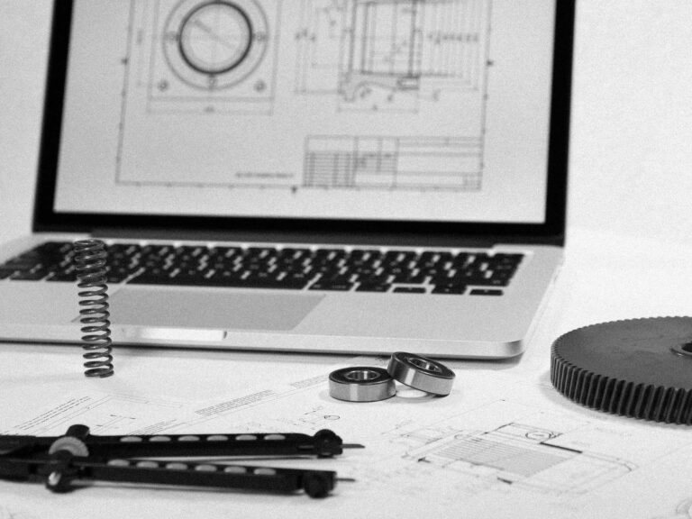 Komponenty mechaniczne i rysunek techniczny CAD na laptopie w procesie projektowania 3D