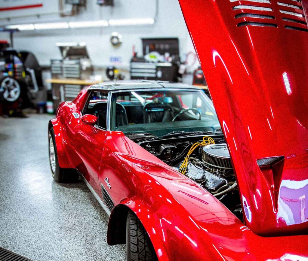 Red classic sports car with the hood open in an auto workshop